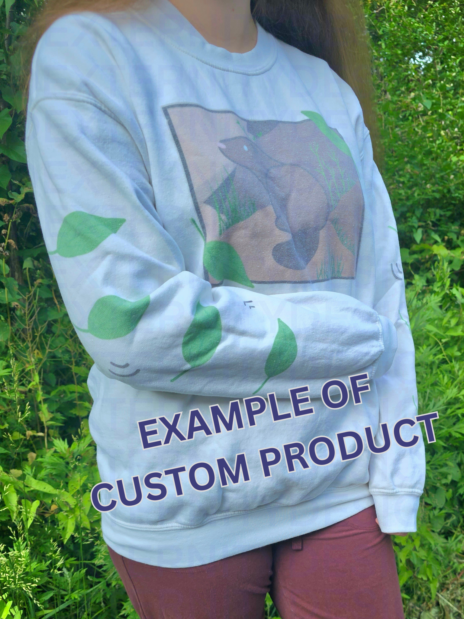 A person with their arm across their stomach wearing a white sweatshirt featuring a groundhog drawing on the chest and leaves on the sleeves. Text on the bottom reads "EXAMPLE OF CUSTOM PRODUCT".