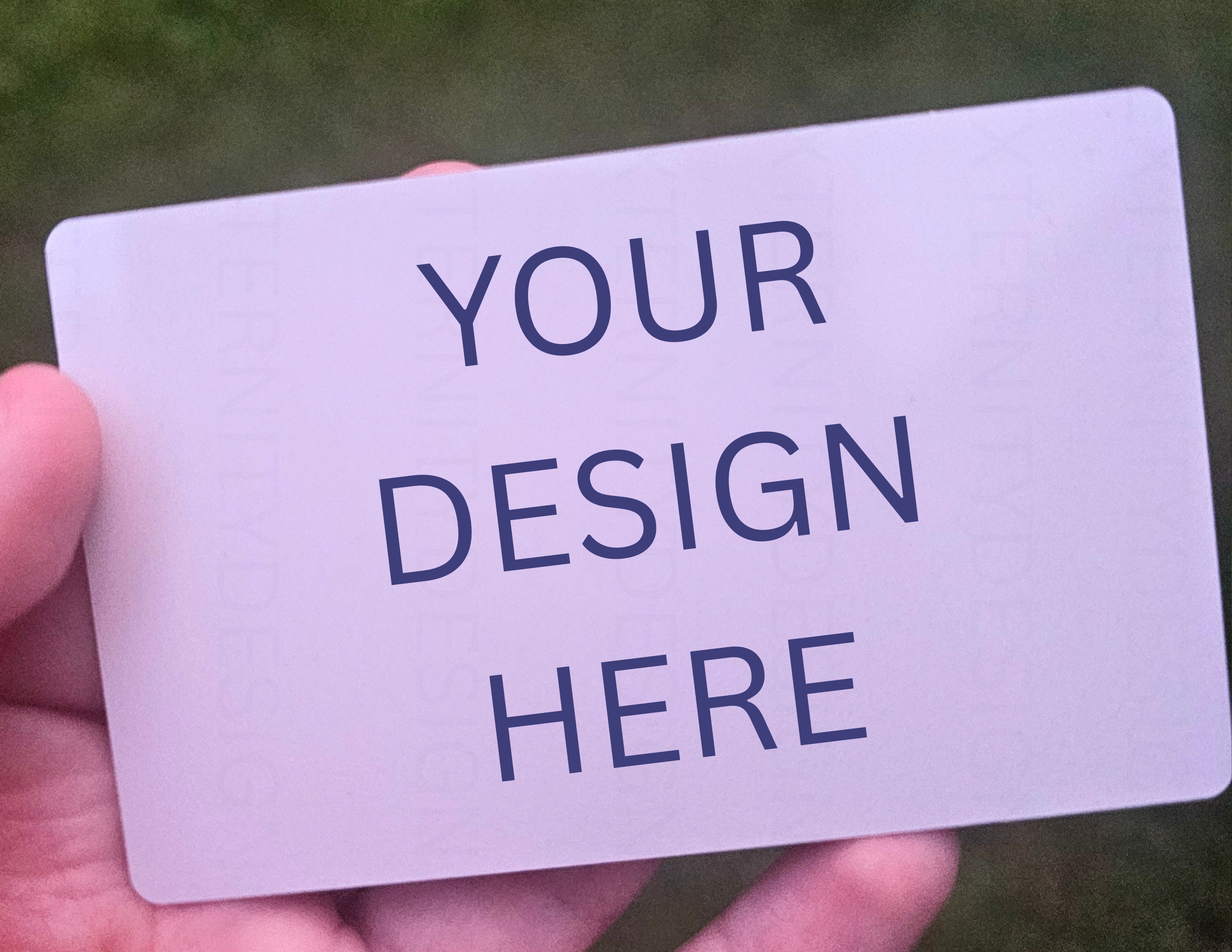 White card with 'Your Design Here' text held by a hand against a blurred green background