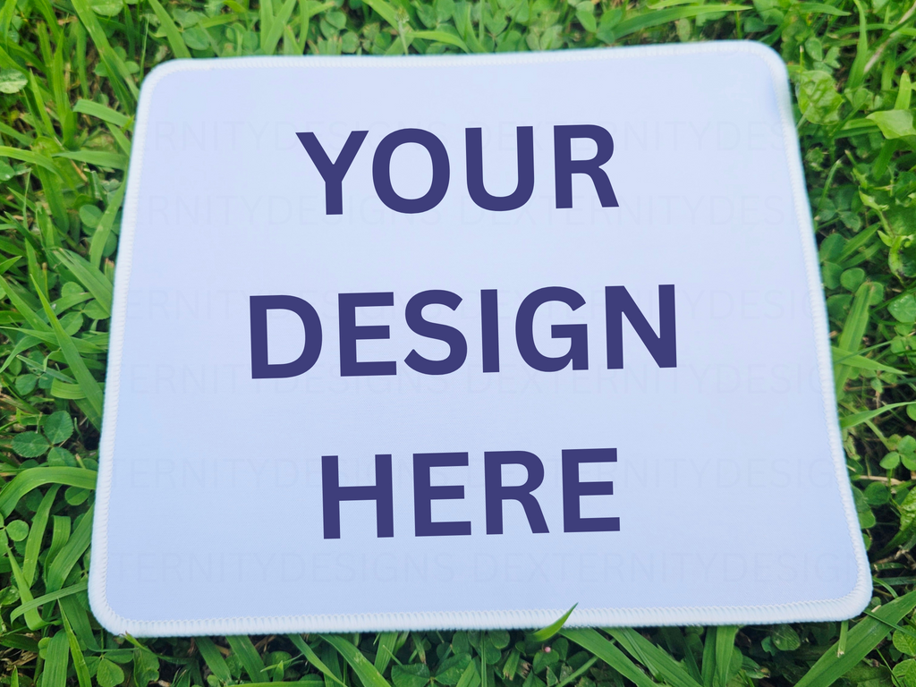 White mousepad with 'Your Design Here' text on grass