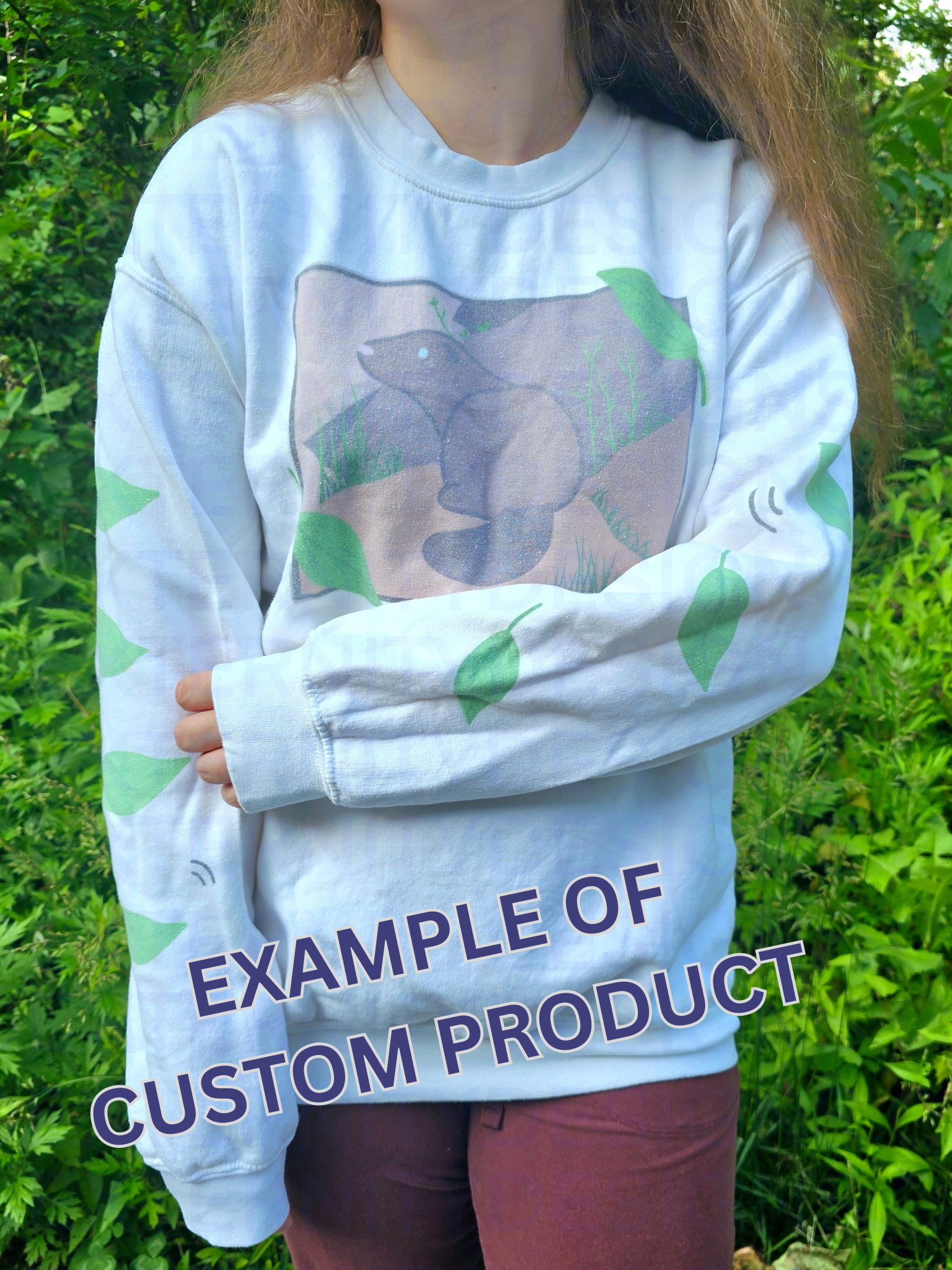 A person with their left arm across their stomach wearing a white sweatshirt featuring a groundhog drawing on the chest and leaves on the sleeves. Text on the bottom reads "EXAMPLE OF CUSTOM PRODUCT".