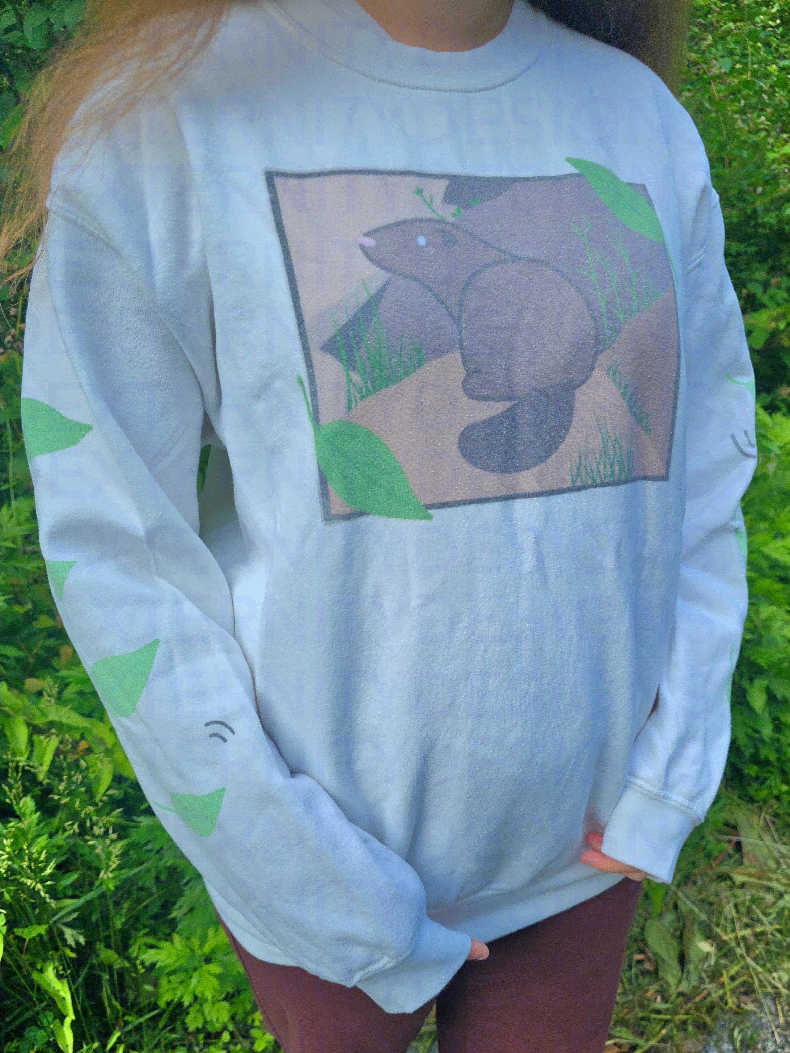 A person wearing a white sweatshirt featuring a groundhog drawing on the chest and leaves on the sleeves.