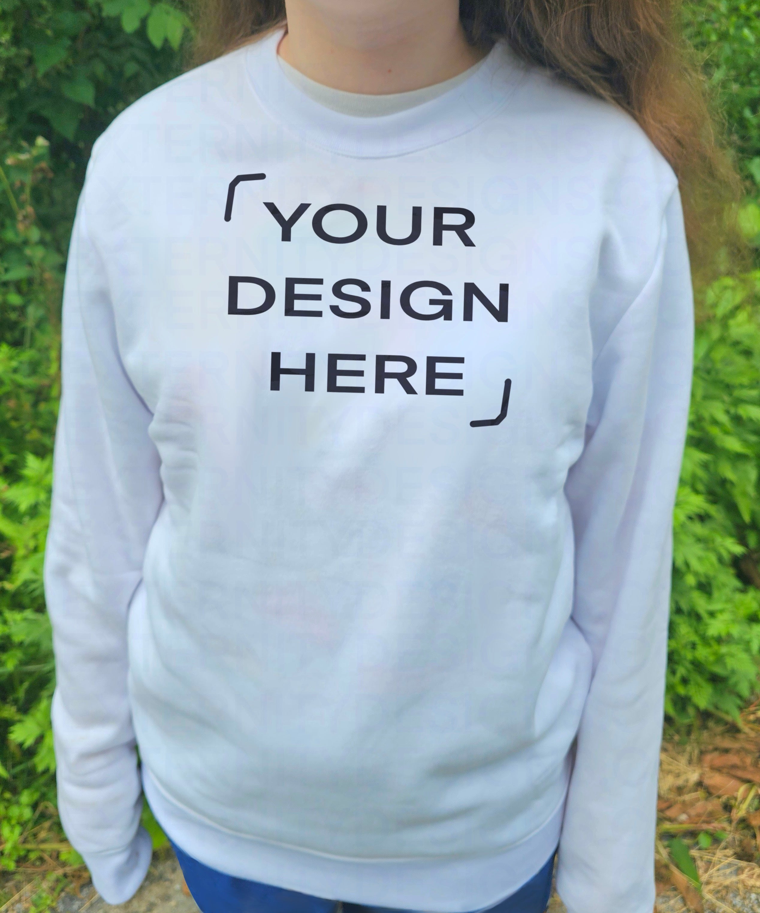 A person wearing a white sweatshirt with "YOUR DESIGN HERE" outdoors.