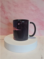 Side view of a mug with a scenic sunrise design on a white platform against a pink marble background