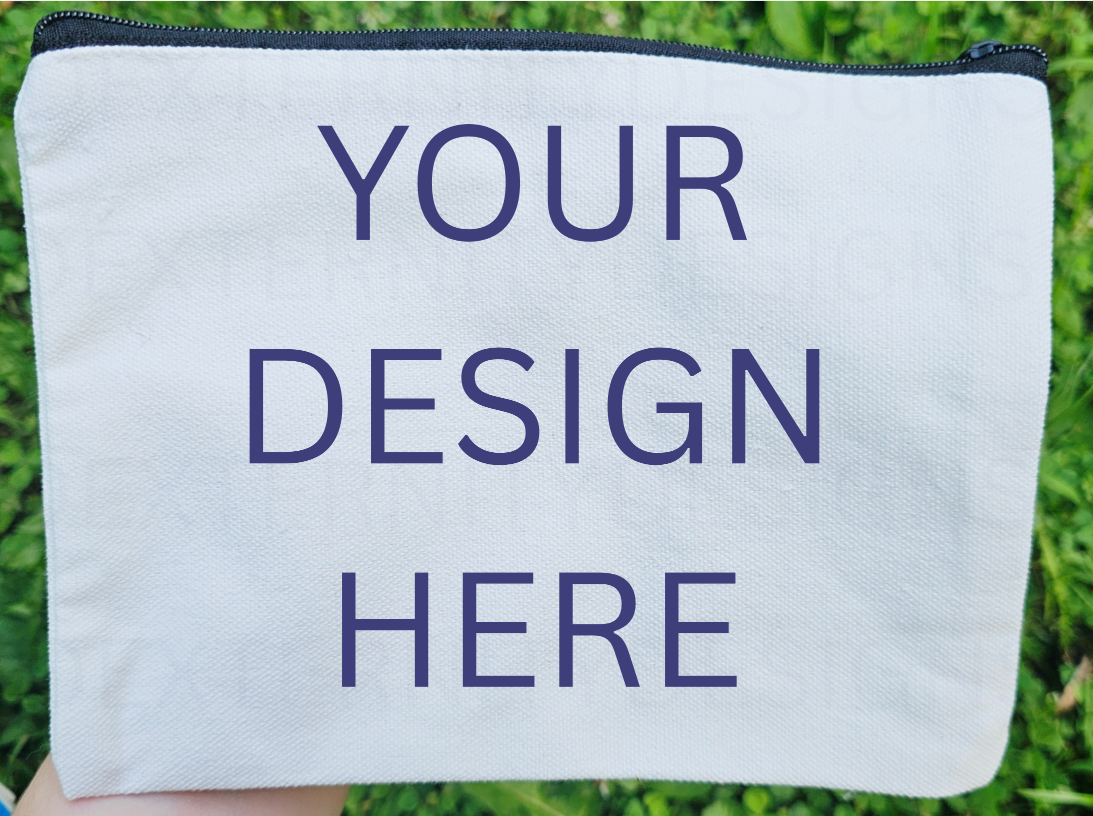 White pouch with 'YOUR DESIGN HERE' text held in front of grass