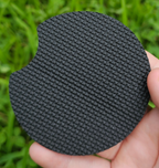 Hand holding a circular coaster designed for car cup holders upside down.